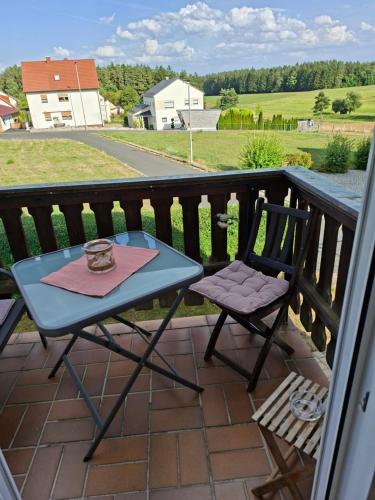 a table and a chair sitting on a balcony at Ferienwohnung am Vogelsteig in Pegnitz