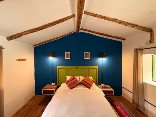 a bedroom with a blue accent wall and a bed at Anido House in Ollantaytambo
