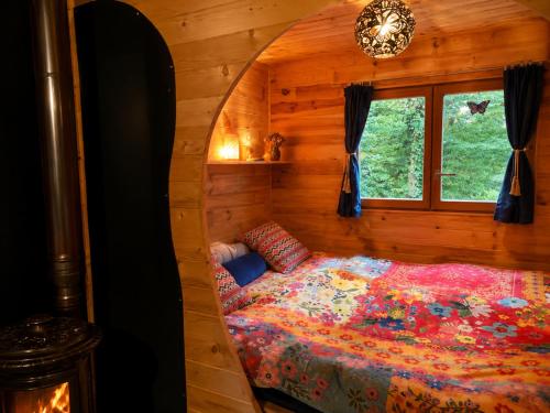 a bed in a wooden room with a window at Roulotte creusoise in Verneiges