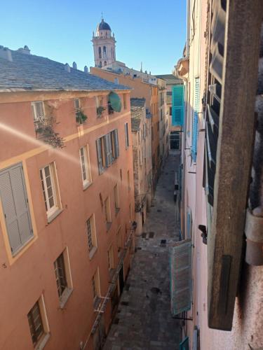 an alley between two buildings with a clock tower in the distance at A casetta in Bastia