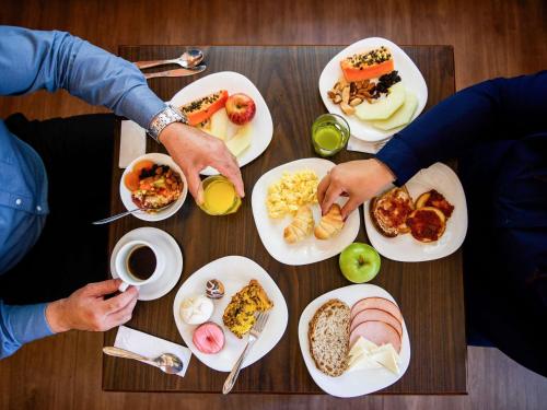 two people sitting at a table with plates of food at ibis Curitiba Batel in Curitiba