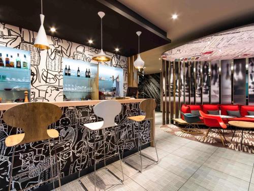 a restaurant with a bar with red chairs at Ibis Bilbao Centro in Bilbao