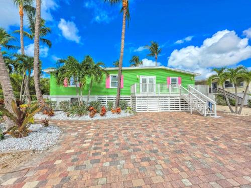 a green house with palm trees in front of it at 275 Ohio in Fort Myers Beach