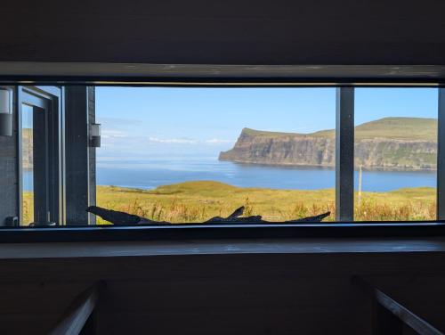 a window with a view of the ocean and cliffs at Luxury Nordic Lodge with private Sauna in Glendale