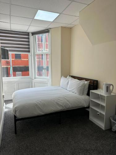a bedroom with a bed and two windows at Victoria Hotel Blackpool in Blackpool
