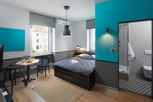 a bedroom with a bed and a table and a bathroom at Studio Apartments River in Rijeka