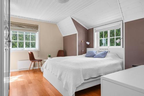 a bedroom with a white bed and two windows at Spectacular nature experience at Norway's southern point! in Svenevik