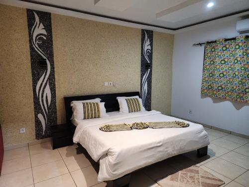 a bedroom with a large bed with white sheets at Nima Resort et Suites in Mandanou