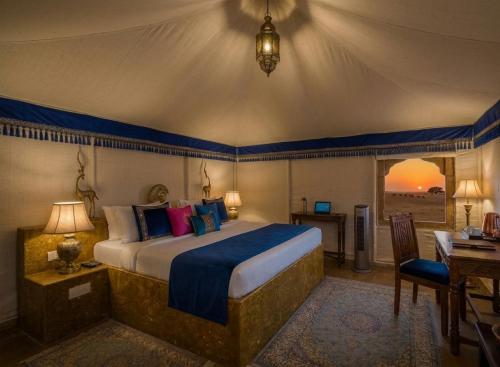 a bedroom with a large bed in a room with a desk at Sam Sand Dunes Camps Jaisalmer in Sām