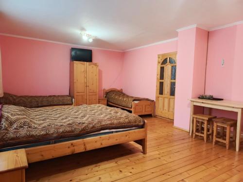 a bedroom with pink walls and a bed and a table at Садиба На лужку in Lazeshchyna