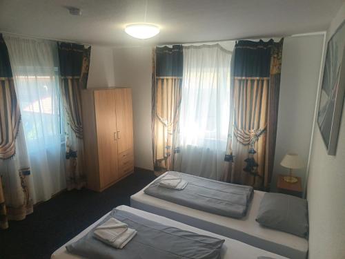 two beds in a room with windows and curtains at Werrapark Apart Heubach in Masserberg