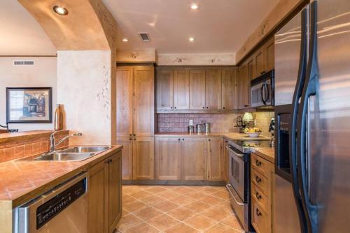 a kitchen with wooden cabinets and a stainless steel refrigerator at Tremblant Prestige - Equinoxe 140-1 in Mont-Tremblant