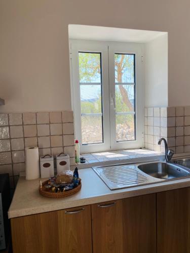 a kitchen counter with a sink and two windows at Matsipeti in Kythira