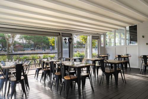 a dining room with tables and chairs and large windows at Cit'Hotel du Cap in Capbreton