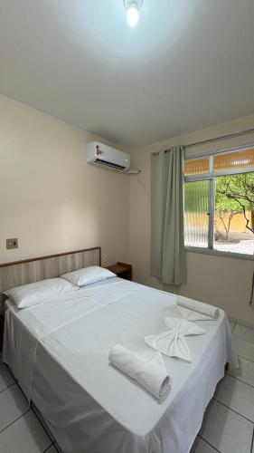 a bedroom with a white bed with two towels on it at Hotel Gold Fish in Corumbá