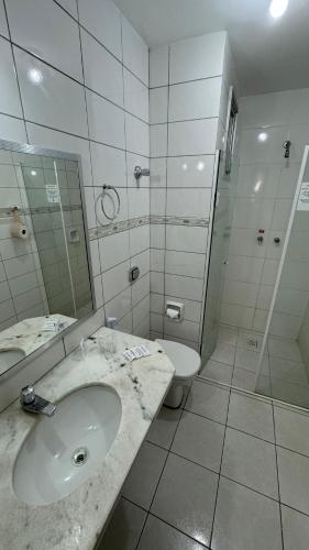 a bathroom with a sink and a toilet and a mirror at Hotel Gold Fish in Corumbá