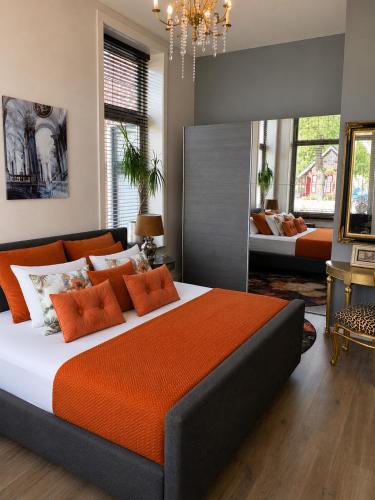 a bedroom with a large bed with an orange blanket at Feel-Fine Guesthouse in Nieuw-Buinen