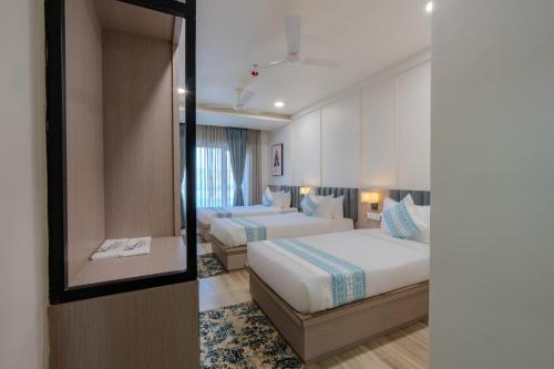 a hotel room with two beds and a mirror at Hotel TGR in Ankleshwar