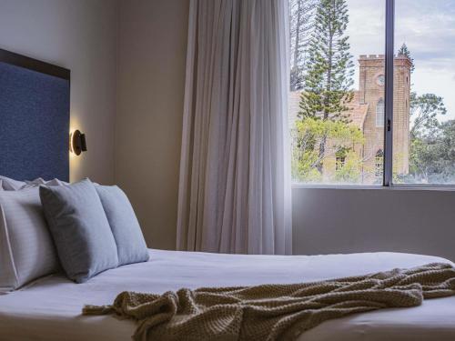 a bedroom with a bed with a large window at Mercure Centro Port Macquarie in Port Macquarie