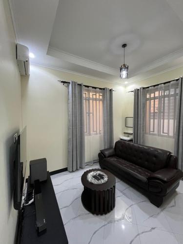 a living room with a black leather couch and a table at Seneu Executive Residence in Mwanza