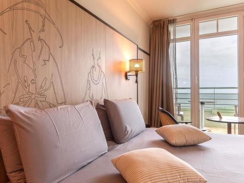 a bedroom with a bed with a view of the ocean at Mercure Granville Le Grand Large in Granville