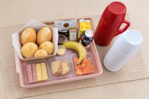 a lunch box with food and a cup on a table at Palm Beach Apart Hotel - Pé na Areia in Florianópolis