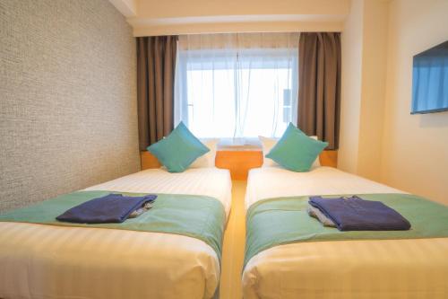 two twin beds in a room with a window at Osaka Kansai Airport Hotel Kansai Airport 2 station in Izumi-Sano