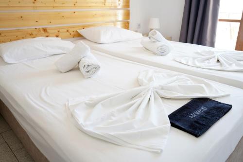 two beds with white sheets and towels on them at Κastro Ηotel in Agios Kirykos