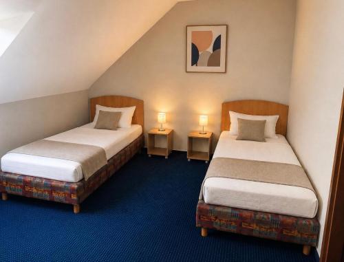 two beds in a room with two lamps on tables at Hotel KM in Darmstadt