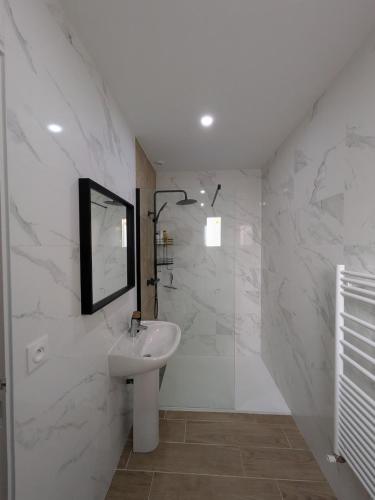 a white bathroom with a sink and a mirror at La Maison Menhiria in Dol-de-Bretagne