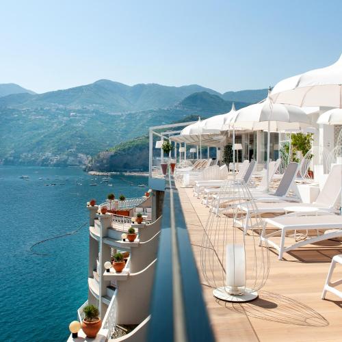 a row of white chairs on a balcony overlooking the water at Hotel Club Due Torri in Maiori