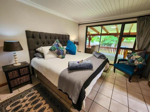 a bedroom with a bed and a chair and a window at Hogsback Misty Oaks Cottage in Hogsback