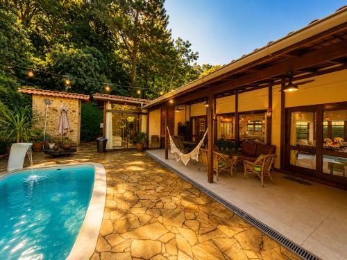 a house with a swimming pool and a patio at Casa Moderna e Espaçosa com Piscina e Lareira na Serra da Cantareira in Mairiporã