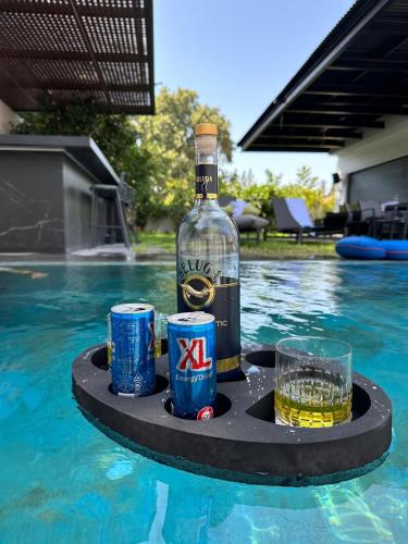 a bottle of alcohol and drinks on a tray in a swimming pool at סוויטת נווה in Pardes H̱anna