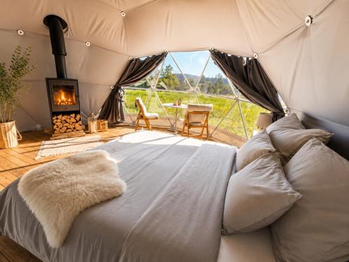 a bed in a tent with a fireplace and a table at Trysil Glamping in Trysil