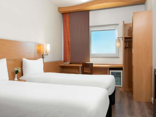 a hotel room with two beds and a window at Ibis Gaziantep in Gaziantep