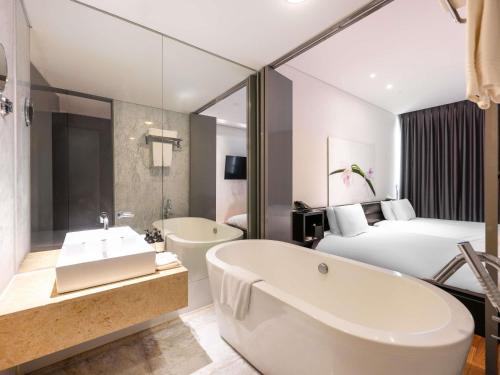 a bathroom with a tub and a bed and a bath tub at Grand Mercure Ambassador Changwon in Changwon