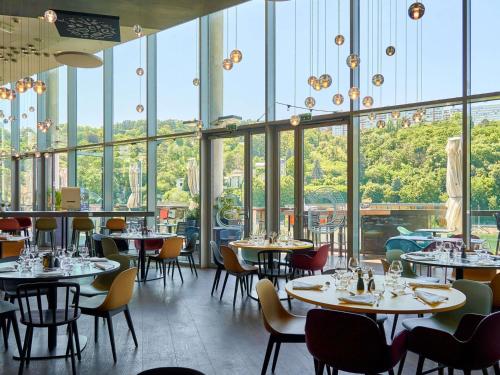 a restaurant with tables and chairs and windows at Novotel Lyon Centre-Confluence Bord de Saone in Lyon