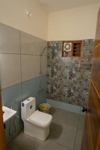 a bathroom with a toilet and a sink at Swastha Royals Wayanad in Kaniyāmbetta