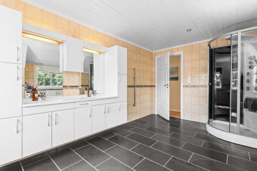 a large kitchen with white cabinets and black appliances at Cozy apartment in South of Norway! in Svenevik