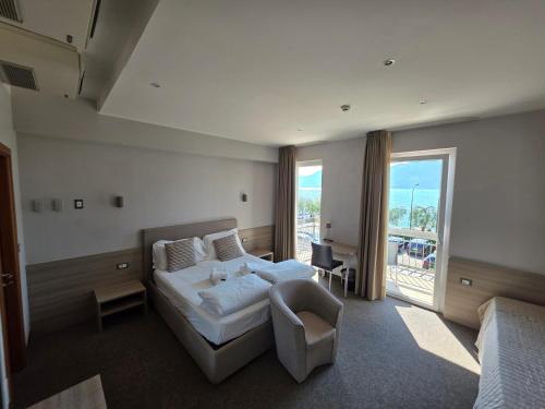 a bedroom with a bed and a chair and a window at Hotel Garni Rosmari in Brenzone sul Garda