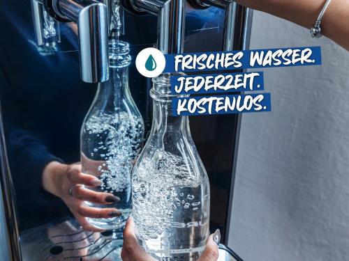 a person is holding a bottle of water at ACHAT Hotel München Süd in Munich
