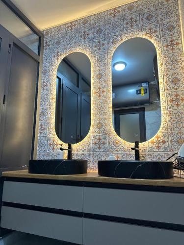 a bathroom with two sinks and two mirrors at Teskey Hostel Karakol in Karakol