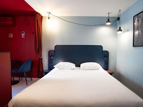 a bedroom with a large white bed with a blue headboard at ibis Styles Bourg-en-Bresse Centre in Bourg-en-Bresse