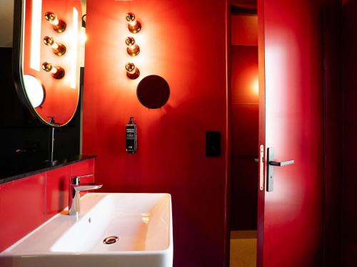 a red bathroom with a sink and a mirror at ibis Styles Bourg-en-Bresse Centre in Bourg-en-Bresse