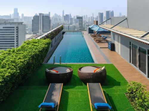 a swimming pool on the roof of a building with chairs at Mercure Bangkok Siam in Bangkok