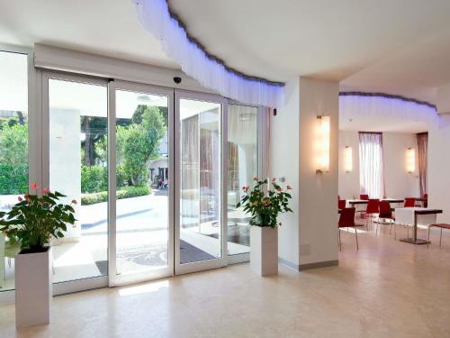 a lobby with glass doors and tables and chairs at Mercure Rimini Lungomare in Rimini