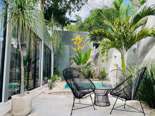 a patio with two chairs and a table and palm trees at Casa Ramon Merida 2 BR AC Private Pool Centro in Mérida