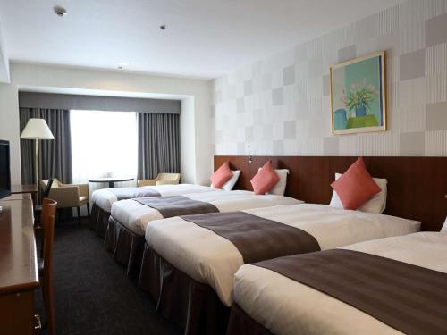 a hotel room with three beds and a television at Loisir Hotel Toyohashi in Toyohashi