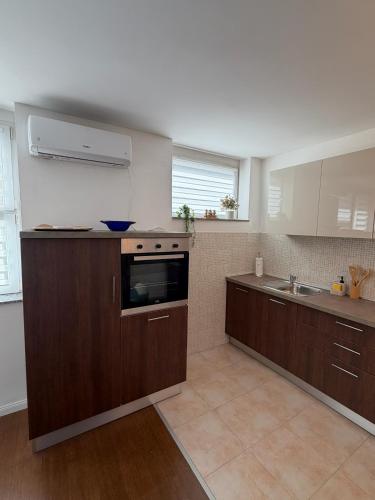 a kitchen with brown cabinets and a sink and a stove at DiSte Apartman in Knin